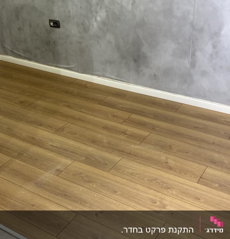 רצפת פרקט עץ חום בחדר עם קיר אפור